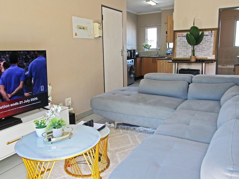 Open plan living area featuring tiled floors and a functional kitchen space with built-in cabinetry and sink.