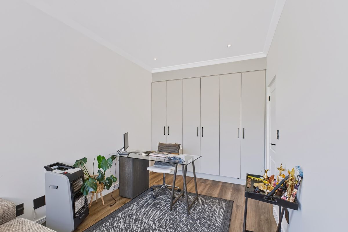 A well-maintained bedroom featuring neutral walls, laminate flooring, recessed downlights, and extensive built-in cupboard storage.