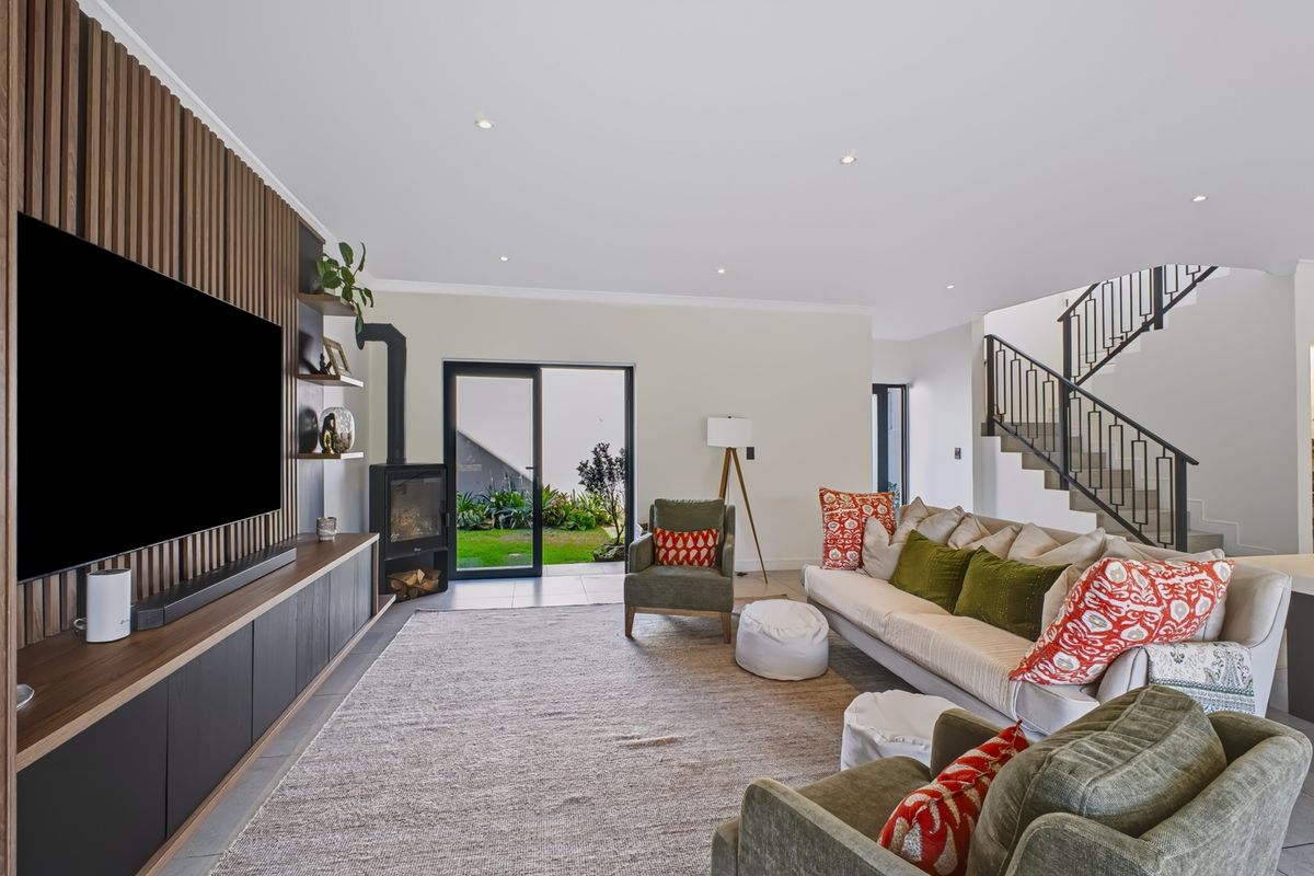 Spacious living room featuring a modern wood-slat feature wall, built-in cabinetry, a sleek fireplace, and direct access to the garden through sliding glass doors.