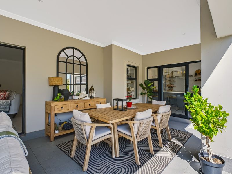 A covered outdoor patio featuring tiled flooring, recessed lighting, and direct access to the interior living and kitchen areas through sliding glass doors.