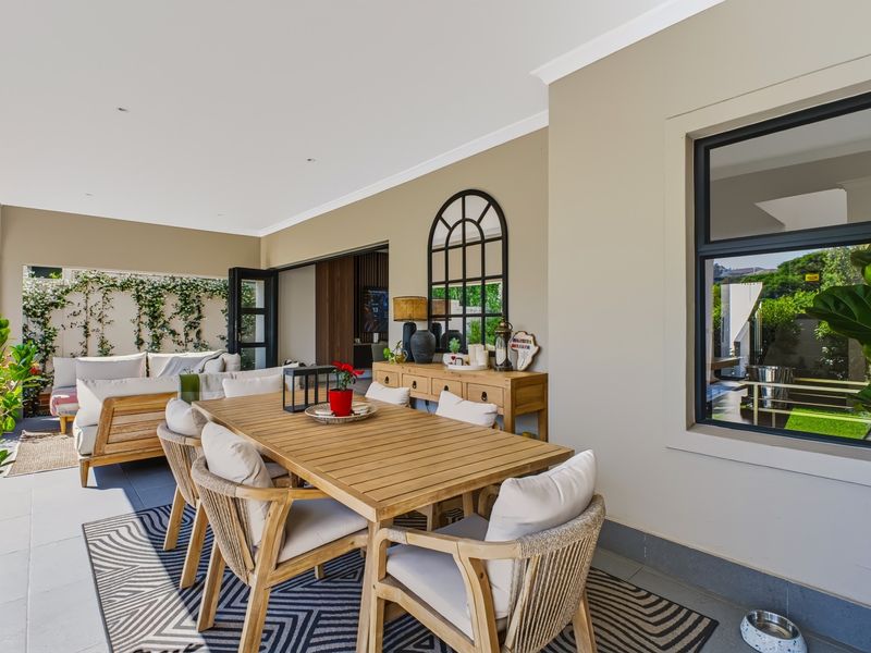A spacious covered patio featuring tiled flooring, recessed lighting, and large sliding glass doors, providing a seamless transition to the indoor living area.