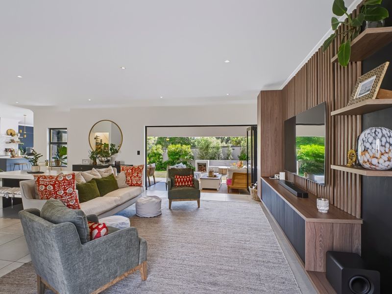 Spacious open-plan living area featuring a modern timber slat feature wall, built-in cabinetry, and seamless flow to the outdoor patio through large sliding doors.
