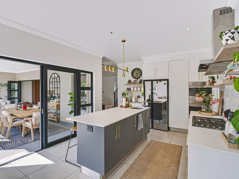 Modern open-plan kitchen featuring a central island, stone countertops, and seamless flow to the outdoor patio through large sliding glass doors.