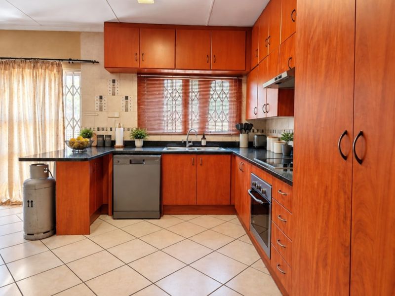 A functional kitchen featuring warm-toned wooden cabinetry, granite countertops, integrated oven, and tiled flooring, offering a practical layout for daily meal preparation.