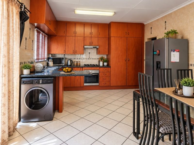 Functional kitchen featuring warm-toned wooden cabinetry, granite countertops, built-in oven with gas hob, and tiled flooring, offering a practical layout for daily cooking.