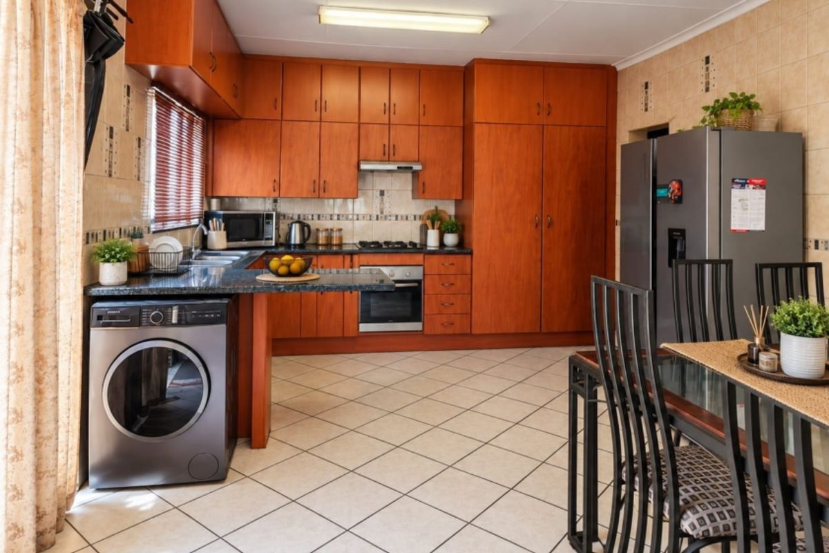 Functional kitchen featuring warm-toned wooden cabinetry, granite countertops, built-in oven with gas hob, and tiled flooring, offering a practical layout for daily cooking.