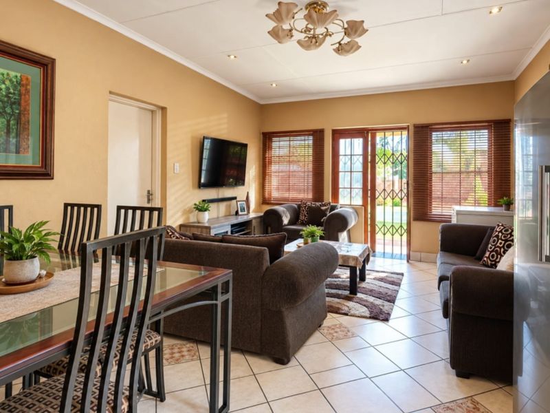 An open-plan living and dining area featuring tiled floors, recessed lighting, and direct access to the outdoor space through a security-fitted sliding door.