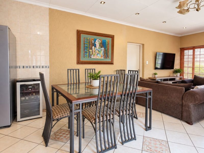 Open-plan living and dining area featuring tiled flooring, recessed downlighting, and a tiled feature wall, creating a functional and connected living space.