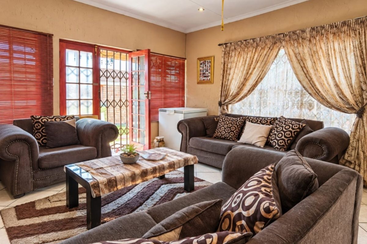 A comfortable living room featuring tiled flooring, recessed lighting, and direct access to the outdoors through classic french doors with security gates.