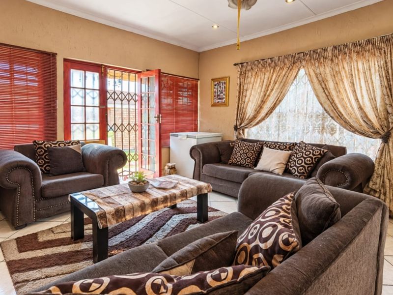 A comfortable living room featuring tiled flooring, recessed lighting, and direct access to the outdoors through classic french doors with security gates.