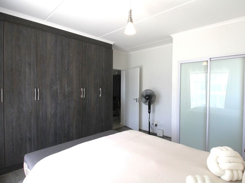 A well-maintained bedroom featuring extensive dark wood built-in cupboards and a secondary sliding door wardrobe, providing ample storage space.