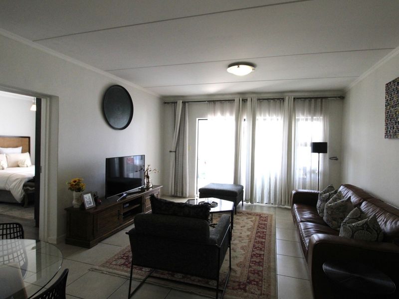 A well-maintained living room featuring tiled flooring, coved ceilings, and a sliding glass door providing natural light and access to the exterior.