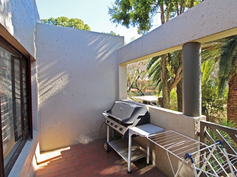 A covered balcony featuring brick flooring, a structural concrete column, and access to the interior via a sliding glass door.