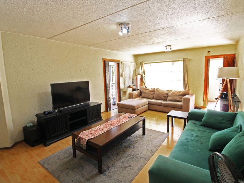 A spacious living room featuring laminate flooring, textured walls, and direct access to an outdoor area through a sliding door.