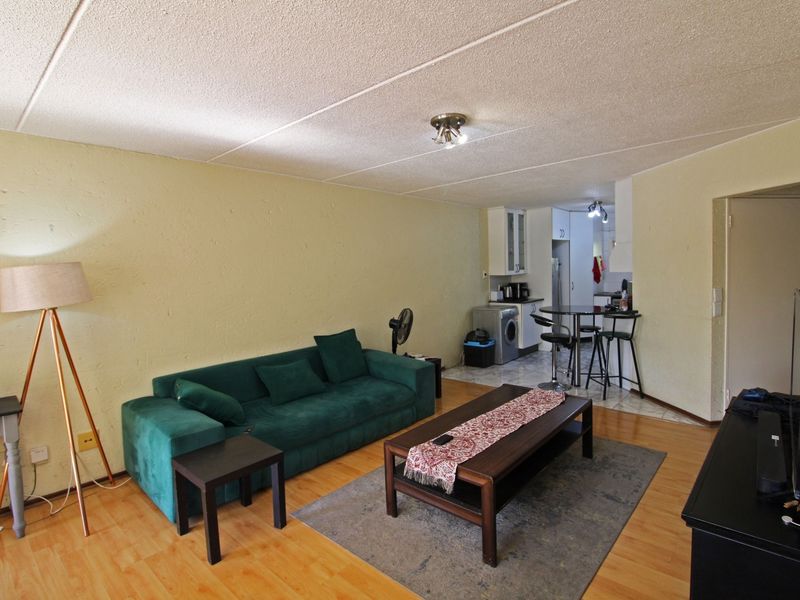 Open plan living area featuring laminate flooring and a connected kitchen space with tiled flooring and built-in cabinetry.