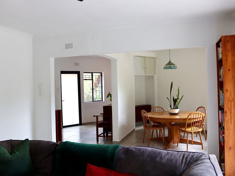 Open plan living and dining area featuring neutral walls, tiled flooring, and a functional layout connecting to an adjacent entrance space.