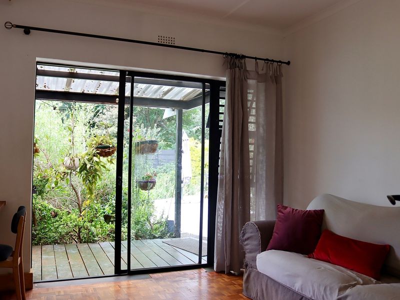 A living room featuring parquet flooring and a large sliding glass door providing direct access to an outdoor patio area.