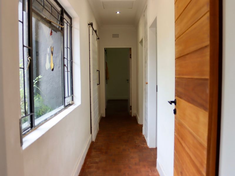 A bright hallway featuring warm parquet flooring, a sliding barn door, and a timber door, providing access to adjacent rooms.
