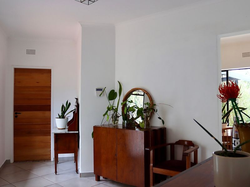 A bright hallway featuring tiled flooring, a solid wooden door, and a security alarm system, providing a clean and functional transition space.