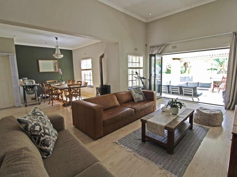 Spacious open-plan living and dining area featuring laminate flooring, a cozy wood-burning fireplace, and seamless access to the outdoor patio through stacking doors.