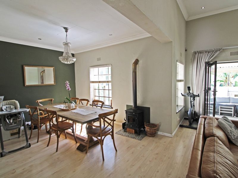 Spacious open-plan living and dining area featuring light laminate flooring, a cozy wood-burning fireplace, and bi-fold doors leading to an outdoor patio.