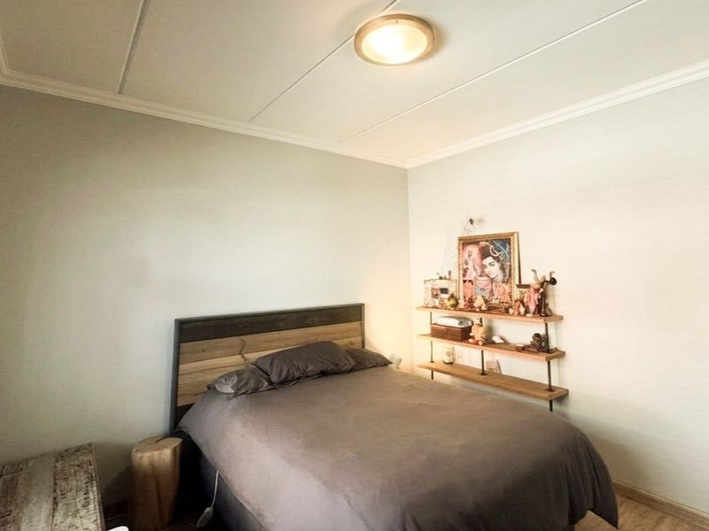 A bedroom featuring crown molding, a ceiling light fixture, and window blinds, providing a functional and neutral space.