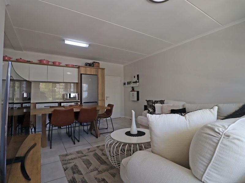 An open-plan living and dining area featuring tiled floors and a modern kitchen with built-in cabinetry and integrated appliances.