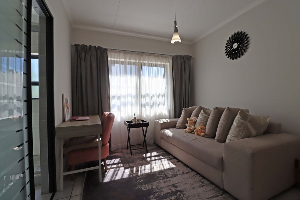 A well-lit living room featuring neutral walls, coving, and a sliding door leading to an adjacent space.