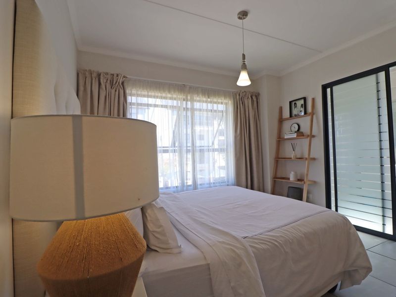 A well-maintained bedroom featuring tiled flooring, a pendant light, and a sliding glass door providing access to an adjoining bathroom.