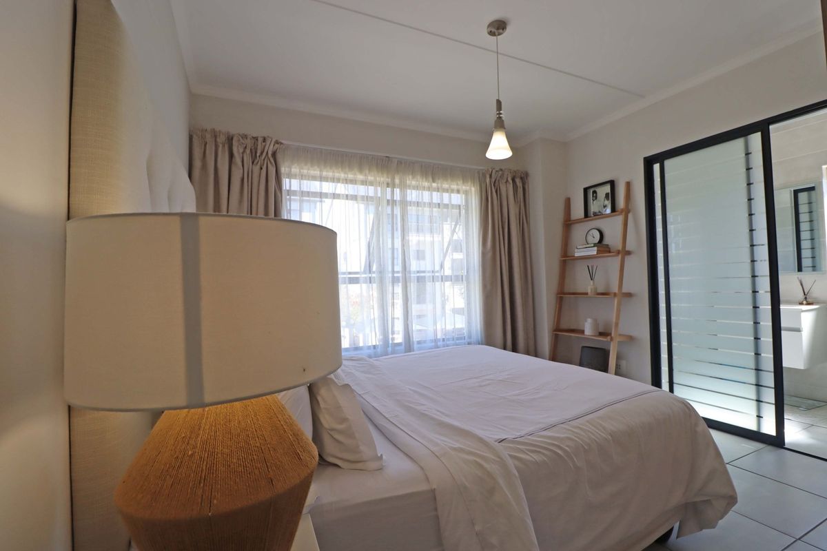 A well-maintained bedroom featuring tiled flooring, a pendant light, and a sliding glass door providing access to an adjoining bathroom.