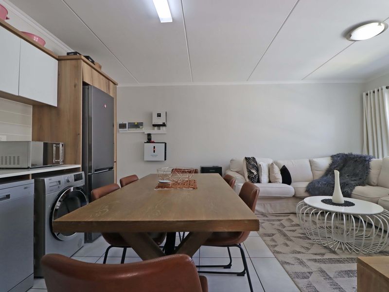 An open-plan living and kitchen area featuring tiled floors, modern cabinetry, and an integrated inverter system, creating a functional and cohesive living space.
