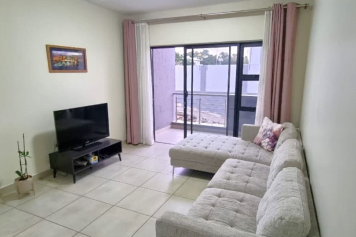 A living room featuring tiled flooring and a sliding glass door providing direct access to a private balcony.