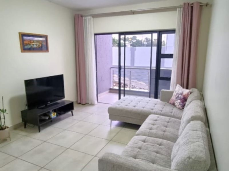 A living room featuring tiled flooring and a sliding glass door providing direct access to a private balcony.