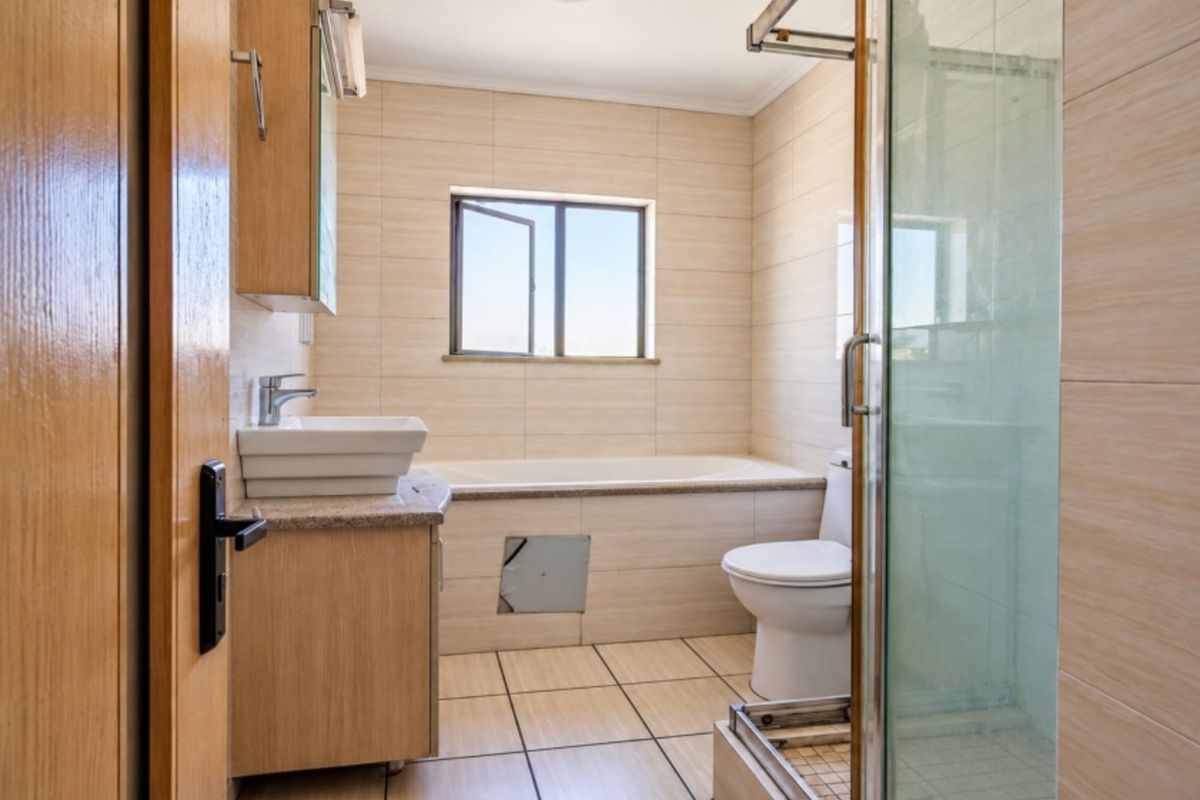 A functional bathroom featuring a built-in vanity, bathtub, separate shower enclosure, and neutral tiled finishes throughout.