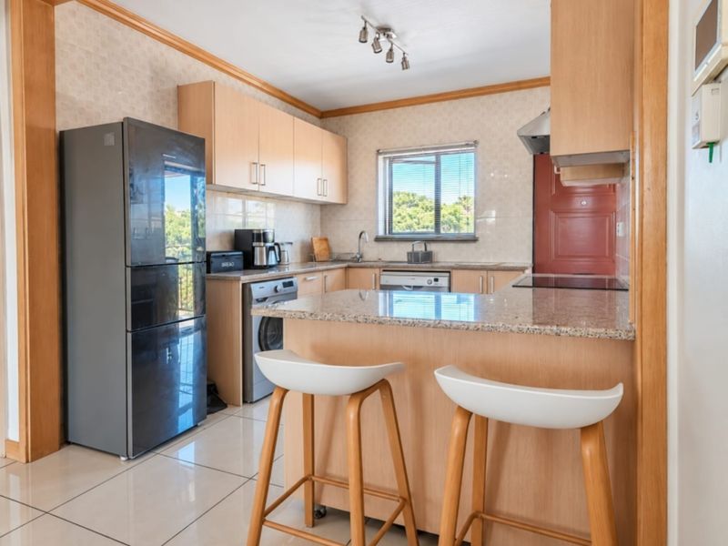 A functional kitchen featuring light wood cabinetry, granite countertops, a breakfast bar, and tiled flooring, offering a practical layout for daily use.