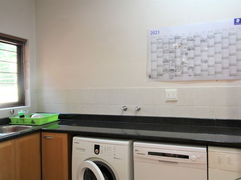 Functional laundry area featuring granite countertops, built-in cabinetry, and dedicated plumbing connections for washing appliances.