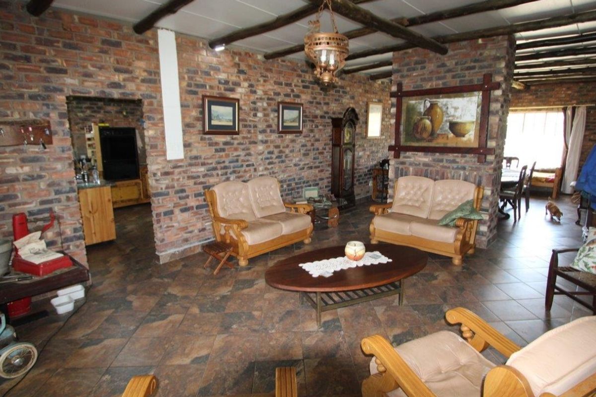 Spacious living area featuring rustic exposed brick walls, traditional timber ceiling beams, and durable tiled flooring, creating a warm and character-filled farmhouse atmosphere.