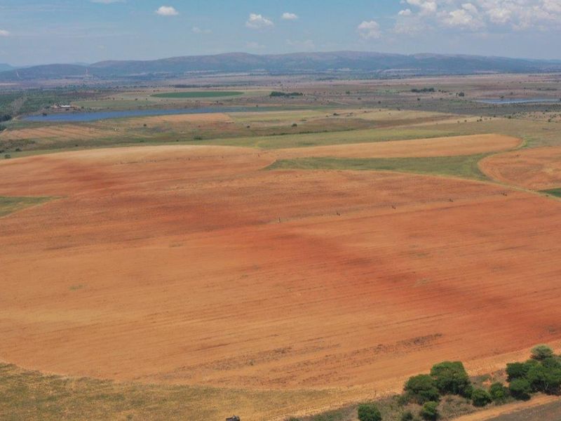 An aerial view of expansive agricultural farmland featuring large circular cultivated fields and irrigation infrastructure set against a vast rural landscape.