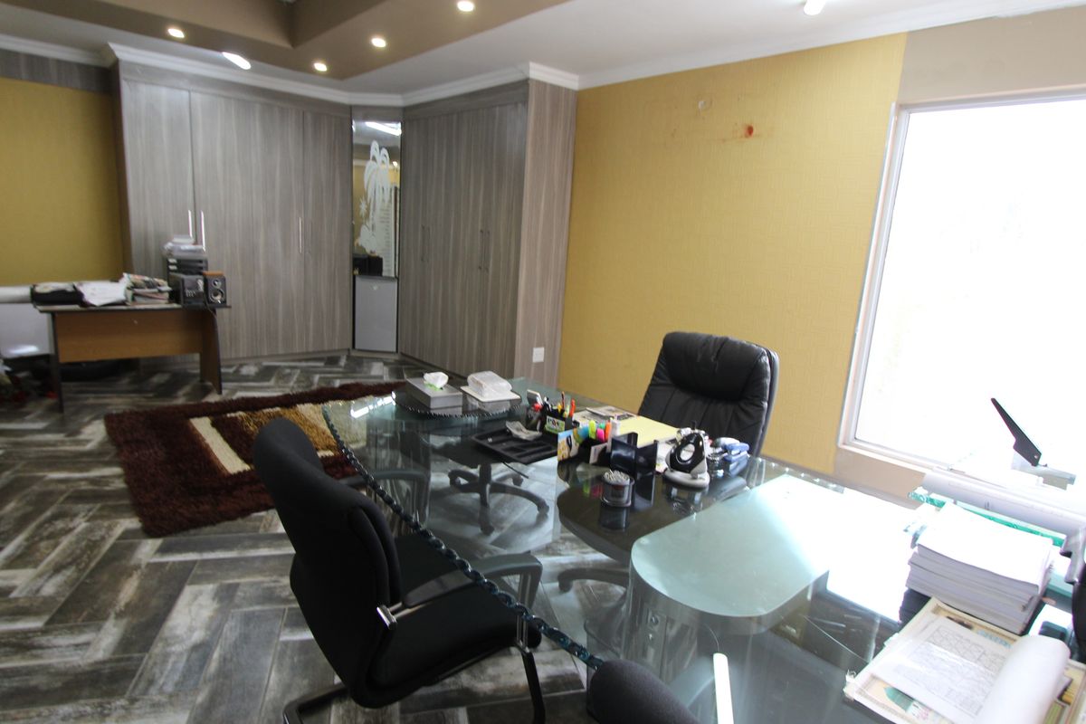 A professional office space featuring built-in cabinetry, recessed ceiling lighting, and patterned tiled flooring, offering a functional workspace environment.