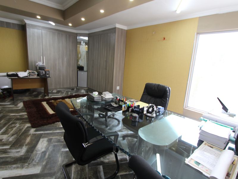 A professional office space featuring built-in cabinetry, recessed ceiling lighting, and patterned tiled flooring, offering a functional workspace environment.