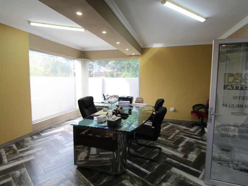 A professional office space featuring herringbone tiled flooring, recessed downlighting, and large corner windows providing ample natural light.