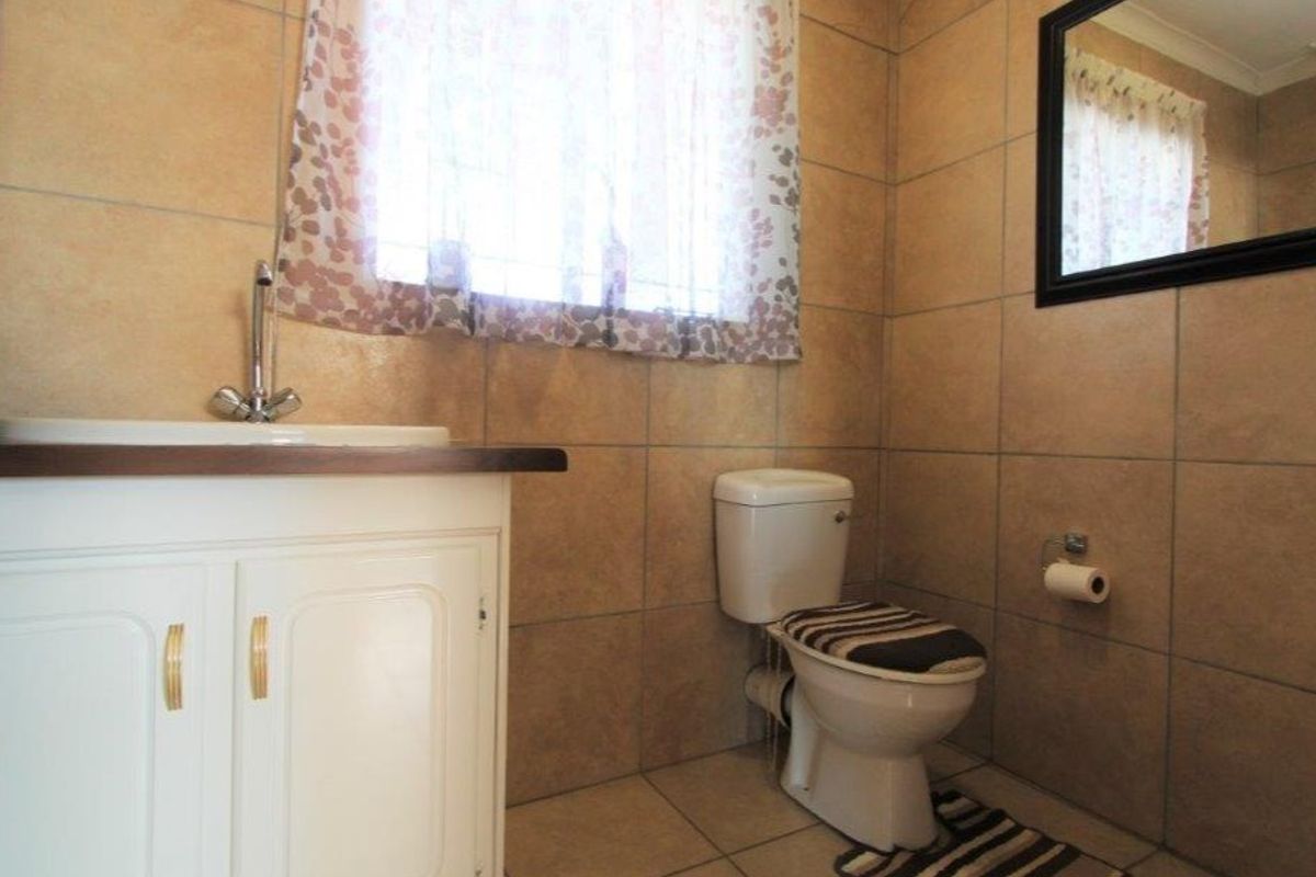 A functional bathroom featuring tiled walls and flooring, a vanity cabinet with a basin, and a standard toilet.