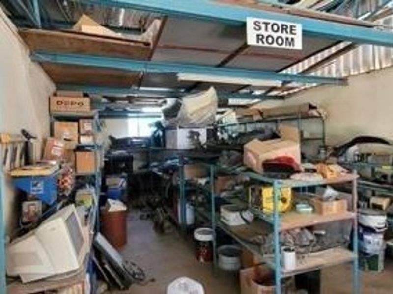 A functional storage room featuring industrial metal shelving units and an exposed steel roof structure, suitable for commercial inventory or equipment storage.