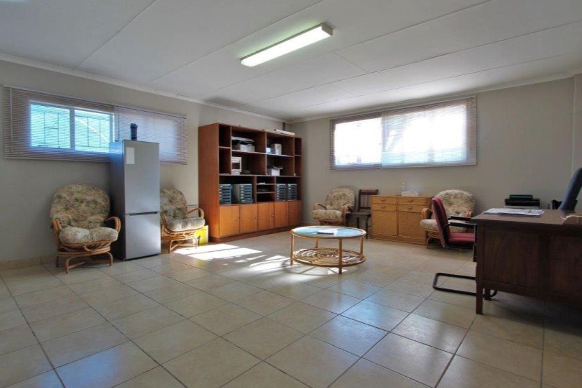 Spacious office area featuring neutral tiled flooring, large windows with venetian blinds, and overhead fluorescent lighting, suitable for a professional workspace.