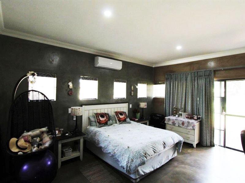 Spacious bedroom featuring dark feature walls, air conditioning, recessed lighting, and direct access to the outdoors through a sliding glass door.