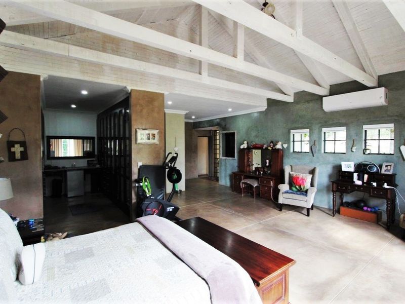 Spacious bedroom featuring a high vaulted ceiling with exposed timber trusses, tiled flooring, and integrated air conditioning.