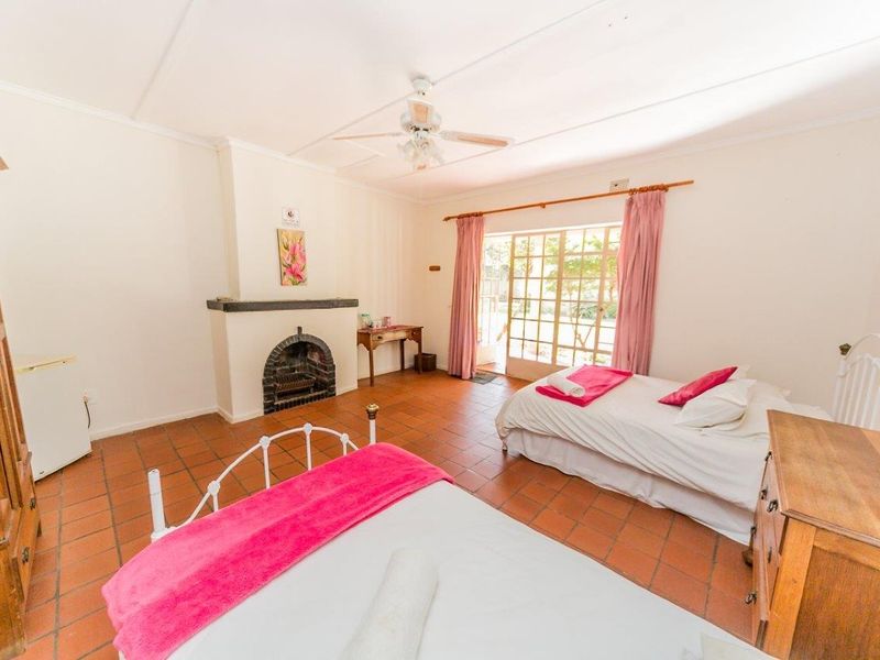 Spacious bedroom featuring terracotta floor tiles, a built-in fireplace, ceiling fan, and direct access to the outdoors through glass-paned french doors.