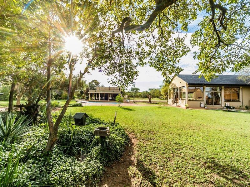 A spacious rear garden featuring a swimming pool, patio area, and mature trees, providing a serene outdoor setting for the farm property.