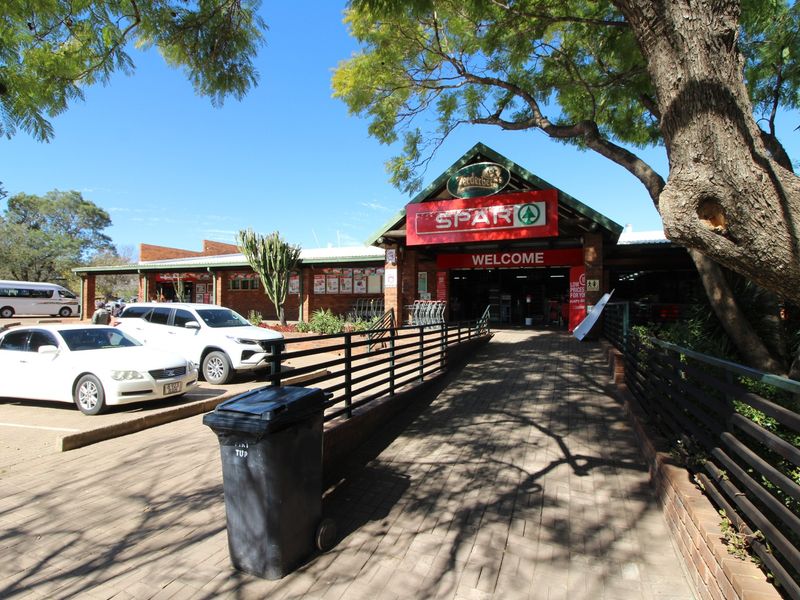 Front entrance view of a retail store featuring brick facade, paved walkway, and metal railings leading to the main customer access point.