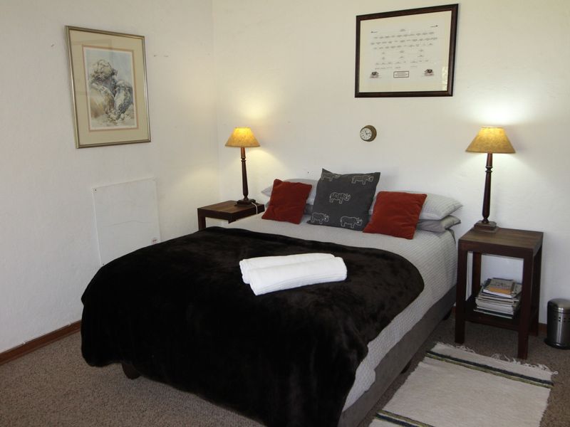 A cozy bedroom featuring carpeted flooring and a wall-mounted heater, providing a comfortable and functional sleeping space.